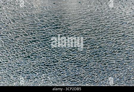 Shattered safety glass presenting a dense network of cracks and fissures, forming an abstract texture or background for concepts like damage, fragilit Stock Photo