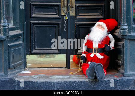 A Santa Claus dall sitting on the steps of a doorway. Stock Photo