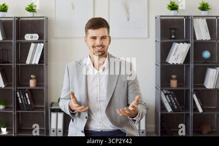 Smiling bearded man office worker dressed in formal suit, shrugging shoulders and looking doubtful Stock Photo