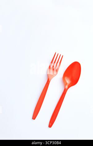 A red plastic fork and spoon placed side by side on a clean white background. Stock Photo