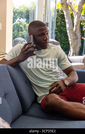 African american man calling smartphone while sitting on sofa at home Stock Photo