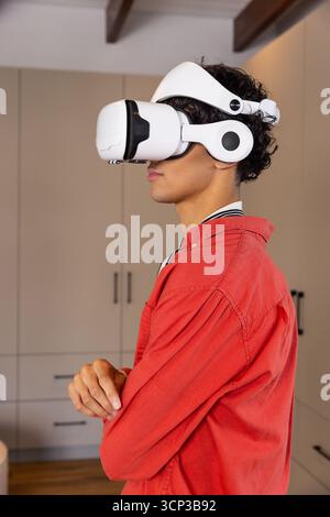 Man crossing arms wearing white vr headset and red jacket standing by cabinets, copy space Stock Photo