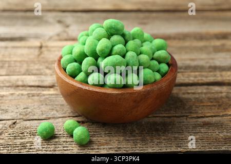 Delicious wasabi coated peanuts in bowl on wooden table, closeup Stock Photo