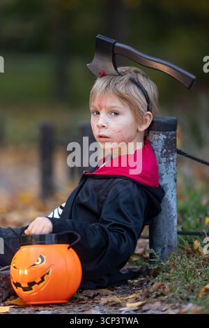 Boy in a forest with Halloween costumes, carved pumpkins with candles and decoration, creepy concept, Halloween theme Stock Photo