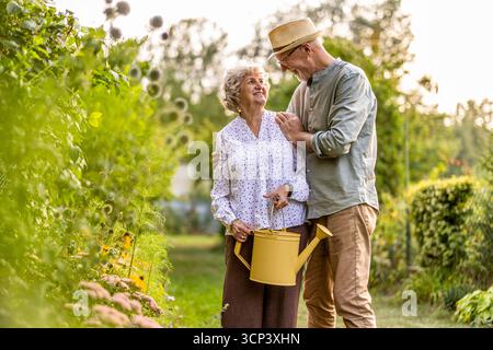 Portrait of happy senior couple standing in the garden on a sunny day Stock Photo
