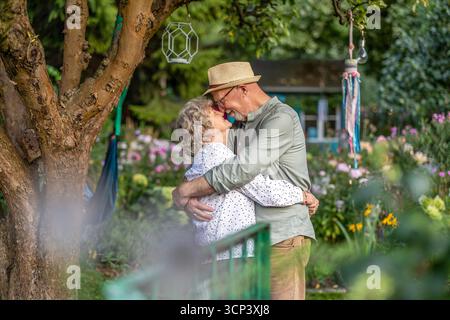 Elderly couple kissing in the garden on a sunny day Stock Photo