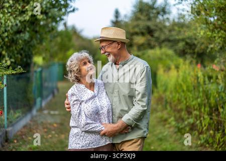 Portrait of happy senior couple standing in the garden on a sunny day Stock Photo