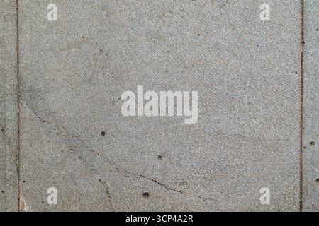 A grey stone wall with a few holes in it. The wall is made of concrete and has a rough texture Stock Photo