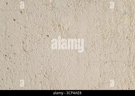 A wall with a white background and a few small holes. The wall is made of cement and has a rough texture Stock Photo