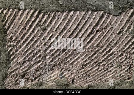 A wall with a pattern of lines and a few spots. The wall is made of concrete. The lines are not very clear and the spots are small Stock Photo