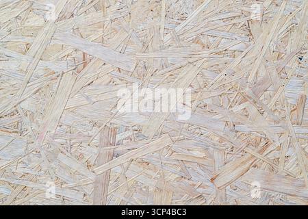 A close up of a piece of wood with a grainy texture. The wood is made up of small pieces of wood, and it is a rough and unfinished surface. Scene is s Stock Photo