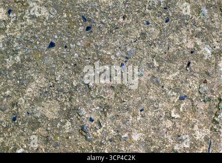 A grey and blue stone surface with small pebbles scattered across it. The pebbles are of various sizes and colors, creating a textured and visually in Stock Photo