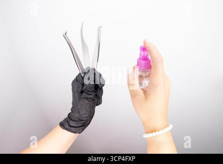 Safe and sterile working conditions in a beauty salon. Hands holding tweezers for eyelash extensions. Stock Photo