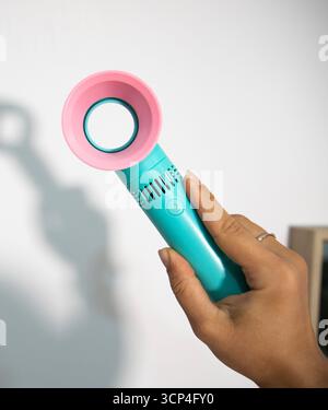 A hand holding a portable mini fan for makeup Stock Photo