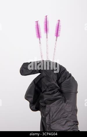 Female makeup artist hand holds pink eyelash and eyebrow brushes Stock Photo