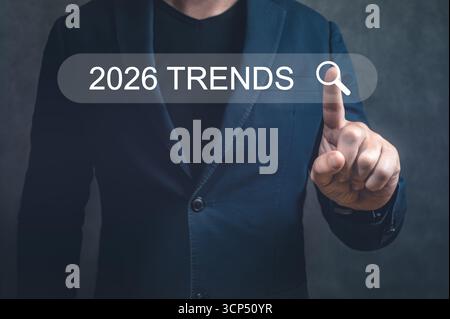 Man in suit using digital interface to find 2026 trends. Represents new ideas, future predictions, and innovative business strategy research Stock Photo