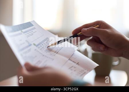Caucasian young adult man holding financial documents and pointing at printed charts with pen, closeup of hands focusing on analyzing data during business meeting or home budgeting Stock Photo