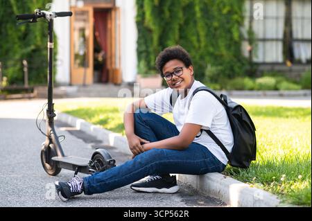 Contented curly-haired boy with a scooter in a living area Stock Photo