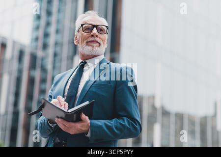 Confident Senior Business Executive Analyzing Notes Outdoors in an Urban City Center Stock Photo