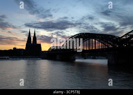 Hohenzollern bridge over the River Rhine and Cologne cathedral silhoetted at sunset, Cologne, North Rhine-Westphalia, Germany, Europe Stock Photo
