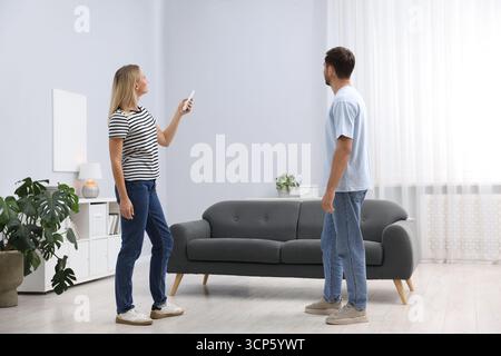 Couple using remote to control air conditioner at home Stock Photo