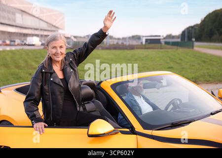 Stylish woman getting out of modern cabriolet outdoors Stock Photo