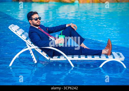 Stylish Businessman Relaxing on a Lounge Chair in a Swimming Pool or a Water Park Stock Photo