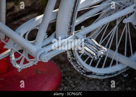 white-painted bicycle close-up of chain set and pedals with traditional spoked wheels. Bicycle painted white. Stock Photo