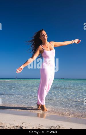 Woman in Pink Dress Posing on a Pristine Beach in Crete Stock Photo