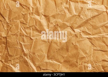 Crumpled brown paper texture background. Old vintage cardboard surface with wrinkles and folds. Recycled craft material detail closeup. Stock Photo