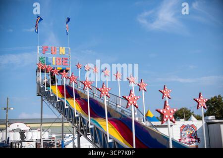 Fun Slide Ride At The Great Frederick Fair Frederick Maryland | FREDERICK, Maryland — The Fun Slide towers over the midway at the Great Frederick Fair, its multicolored lanes and marquee of red star lights framed against a clear autumn sky. Operated by Reithoffer Shows, the ride is one of many traveling amusements set up each year at the Frederick Fairgrounds. The fair dates to 1877 and ranks among the oldest agricultural fairs in the United States. Stock Photo