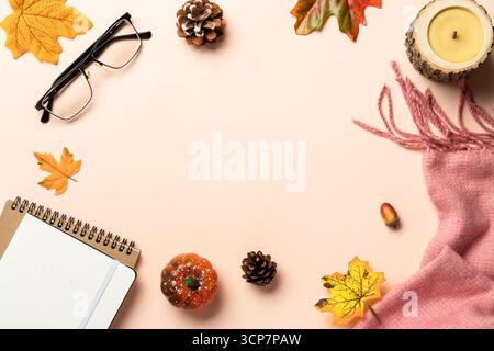 Autumn flat lay background. Autumn leaves, notepad, scarf, candle and spices on yellow background. Stock Photo