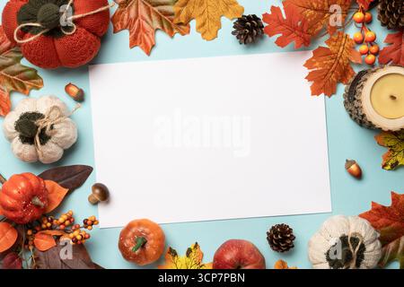 Autumn flat lay background, thanksgiving day concept. Falling leaves, notepad, knitted scarf and wooden candle on blue background. Stock Photo
