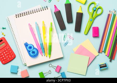 School supplies on blue background. Top view. Notepad, markers, pens, calculator and others. Stock Photo