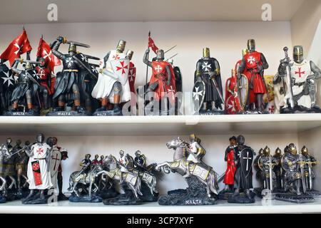 Souvenir figurines of Maltese knights in armor with swords, shields, flags, and horses, displayed on shelves. Stock Photo
