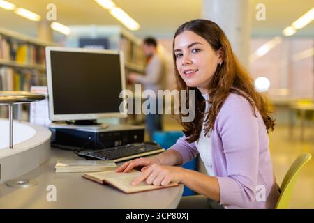 Young woman working with book and computer Stock Photo
