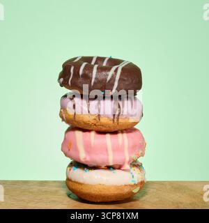 Stack of donuts with different toppings and glazes, green background Stock Photo