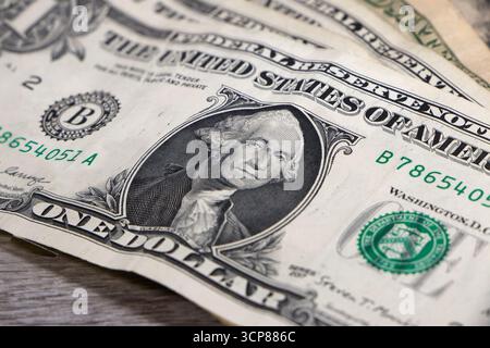 Close-up of a one-dollar bill showing the portrait of George Washington on a wooden surface - us currency, finance, dollar bills Stock Photo
