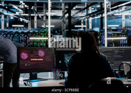 System administrator in server hub trying to protect hardware from hacker attack stealing sensitive information. Data center cybersecurity specialist fighting virus during security breach Stock Photo
