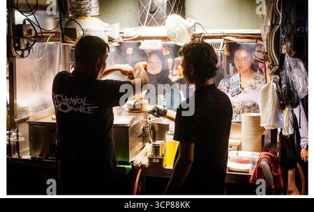 Street vendors serving asian food to customers at a bustling malaysian night market vibrant local culture malaysia Stock Photo