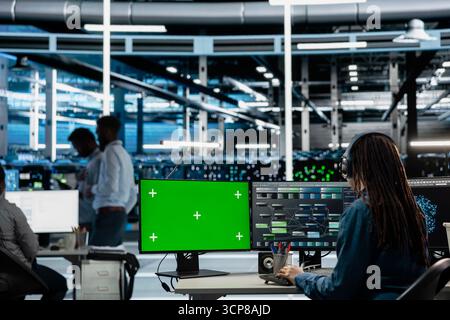 Engineer in server farm using green screen PC to repair equipment storing datasets. IT professional using mockup computer to do debugging on rigs doing computational operations Stock Photo