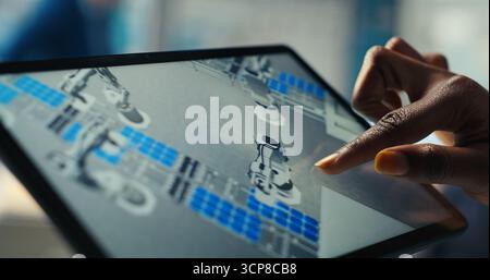 Photovoltaics factory specialist designs production lines in CAD app using tablet. Solar panels plant technician uses simulation software on device to optimize production layouts, camera B closeup Stock Photo