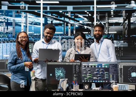 Portrait of smiling server hub engineers using AI algorithms and node trees categorizing and clustering unstructured data. Happy data center coworkers using Natural Language Processing tech Stock Photo