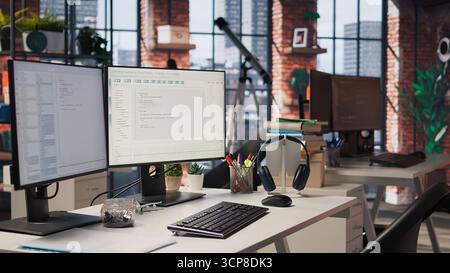 Advanced AI algorithms running on computer monitors in empty startup workspace deploying machine learning models. Coding platform on PC screens in Silicon Valley office, trucking left shot Stock Photo