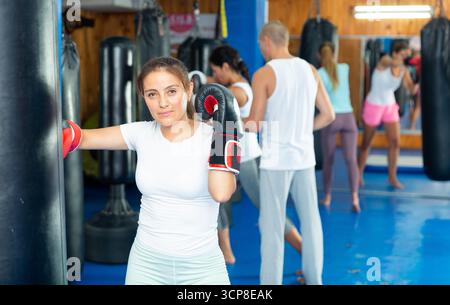 Young Latina in boxing gloves mastering punches on punching bag Stock Photo