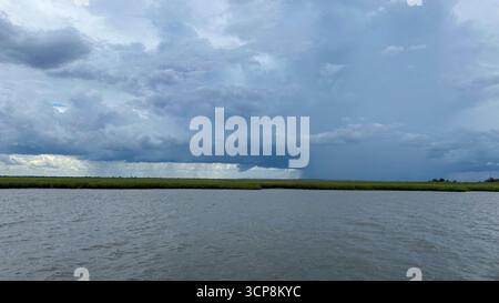 A storm over the land as viewed from the intracoastal waterway with dark clouds and rain Stock Photo