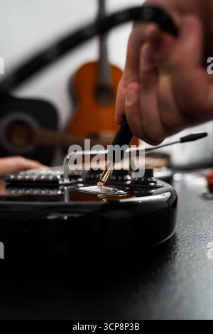 Plugging Cable into Electric Guitar close-up. Jack cable is plugged into the black electric guitar, activating its signal path for rich tones and stag Stock Photo