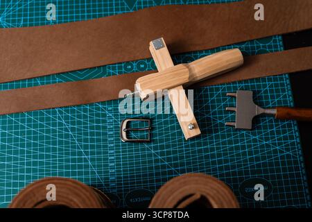 Leathercraft tools and belt-making preparation. Leatherworking setup featuring tools, buckle, and leather strips laid out neatly on a mat, ready for b Stock Photo