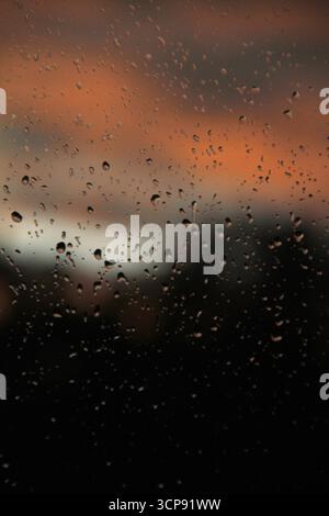 Raindrops on a window, with  a view of the sky at sunset hour Stock Photo