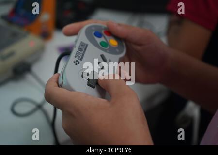 A close-up shot of a girl' s hands holding and using a gray and purple Super Nintendo controller. Stock Photo